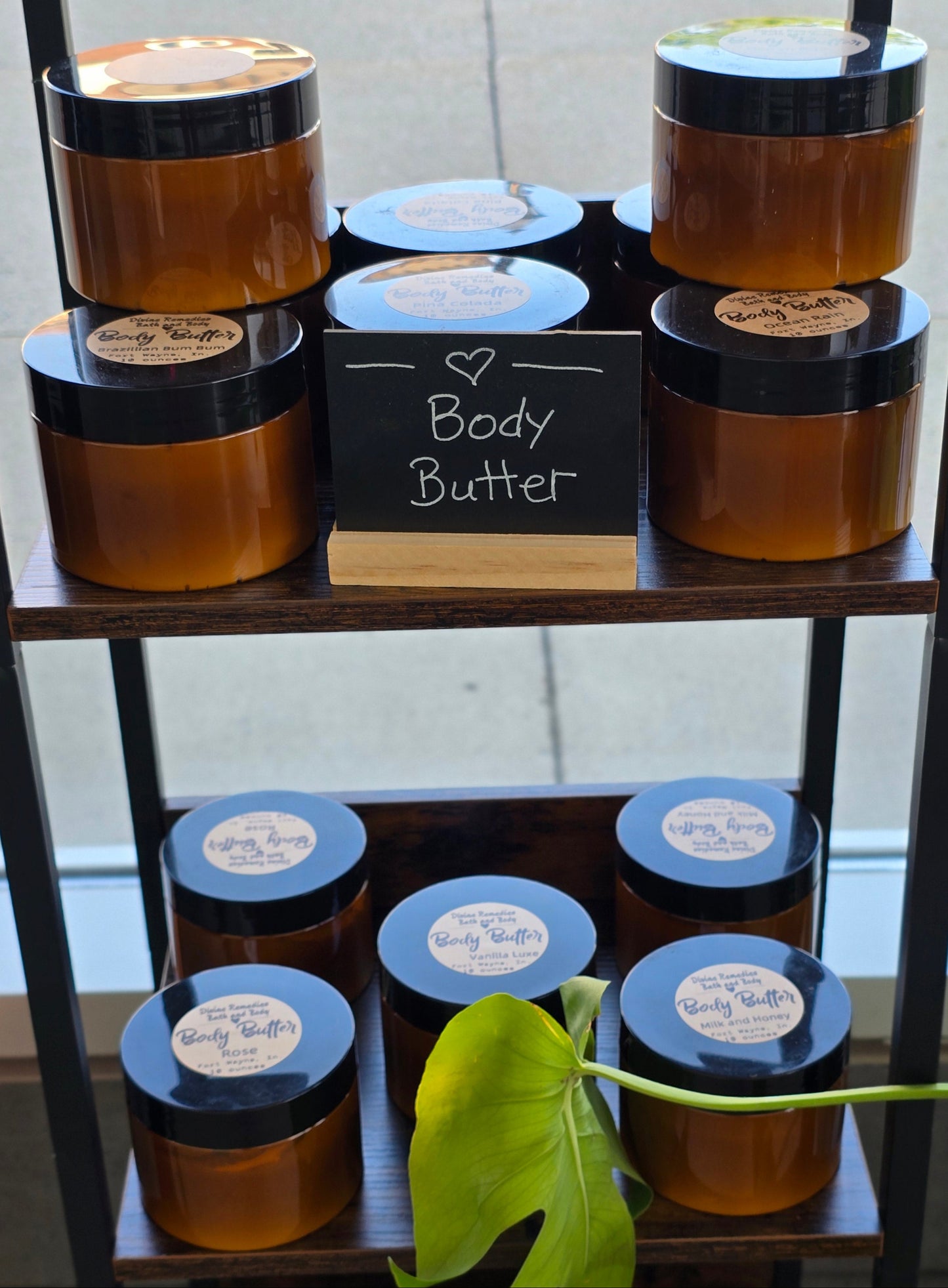 Collection of body butters in a decorative stand with a plant in the background.