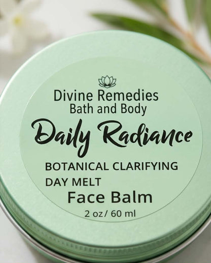 A close-up of a round metal tin of Divine Remedies Daily Radiance Botanical Clarifying Day Melt Face Balm, featuring a pale mint green lid with black text.