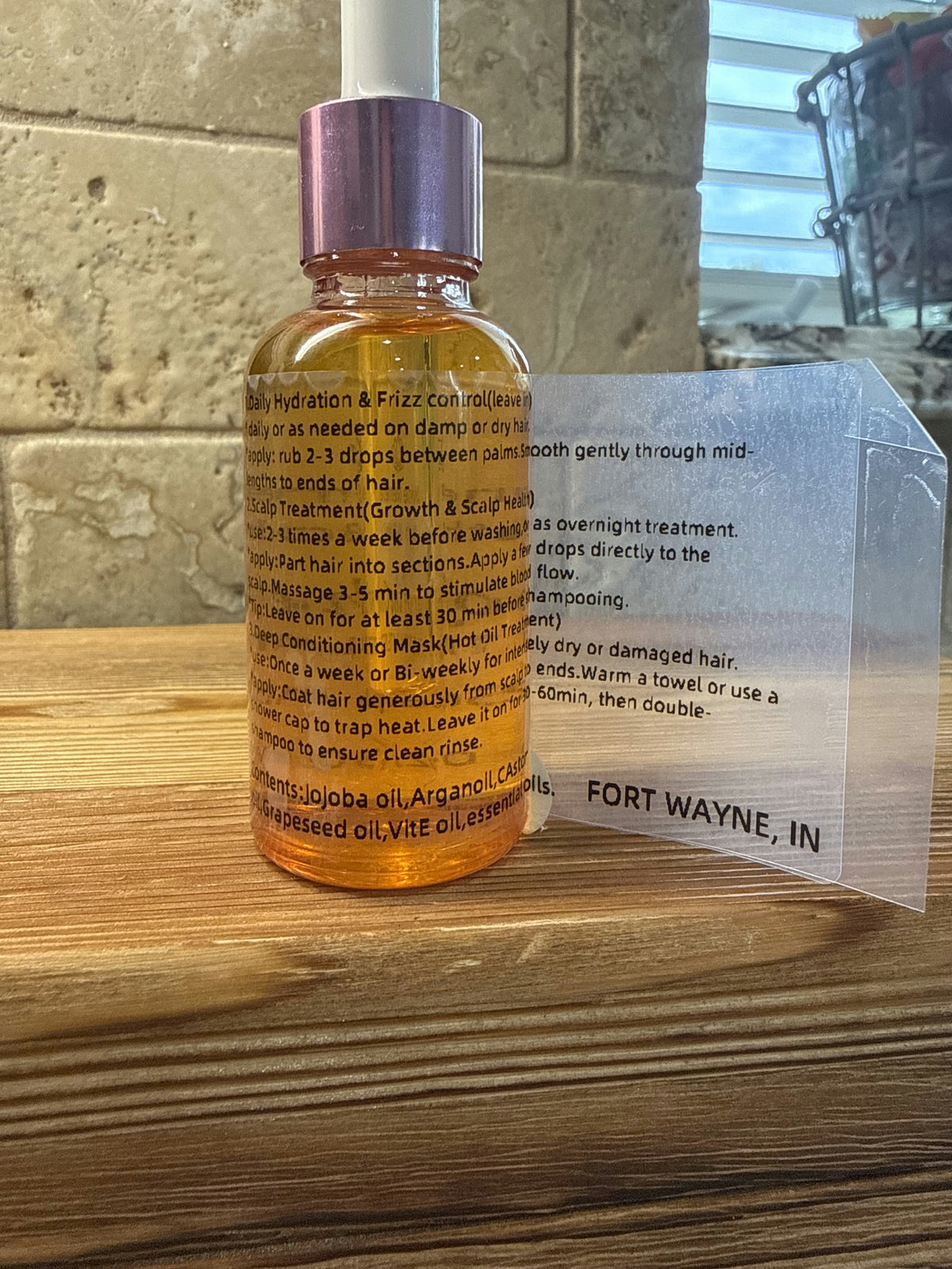 Divine Remedies Nectar of the Crown hair oil bottle on a wooden surface